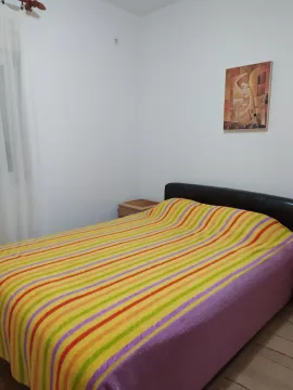 A simple bedroom with a colorful striped bedspread. - image 16