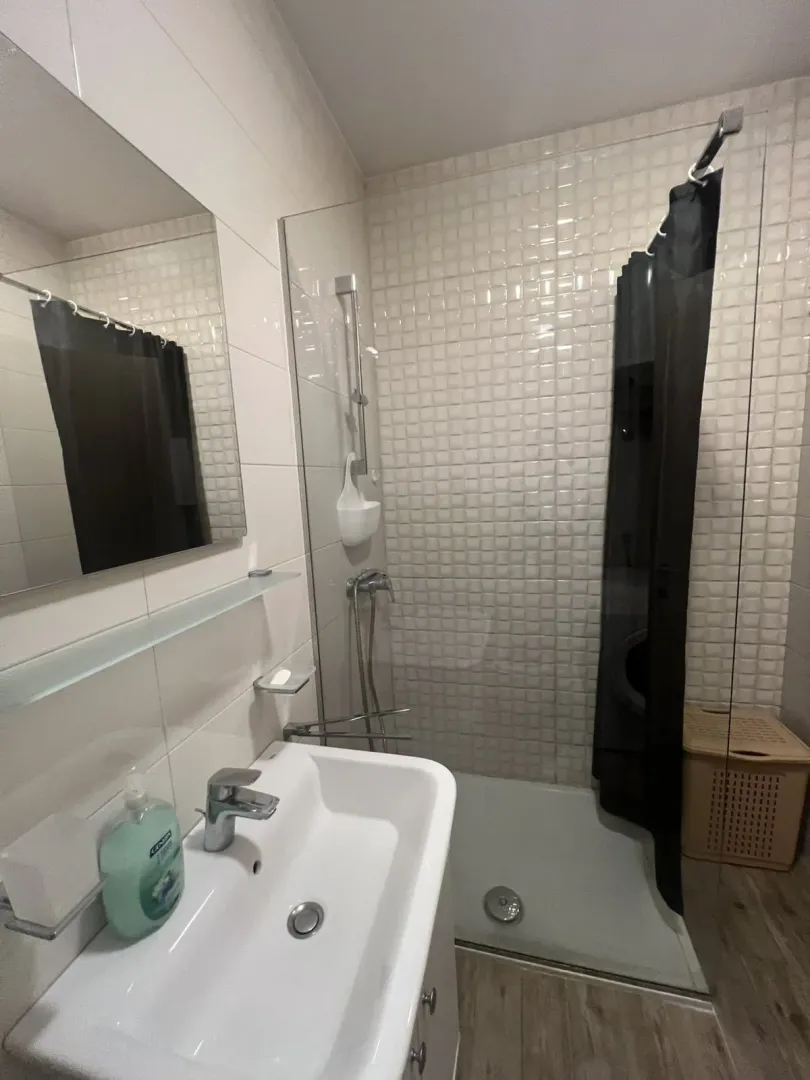 Kupatilo sa tuš kabinom i bijelim lavaboom.