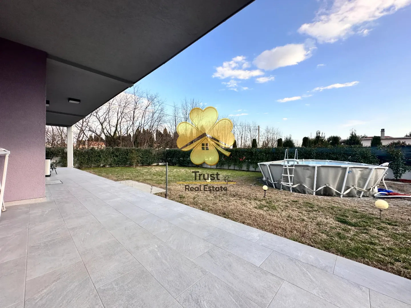 Covered terrace with tiled flooring and a view of the yard and pool.