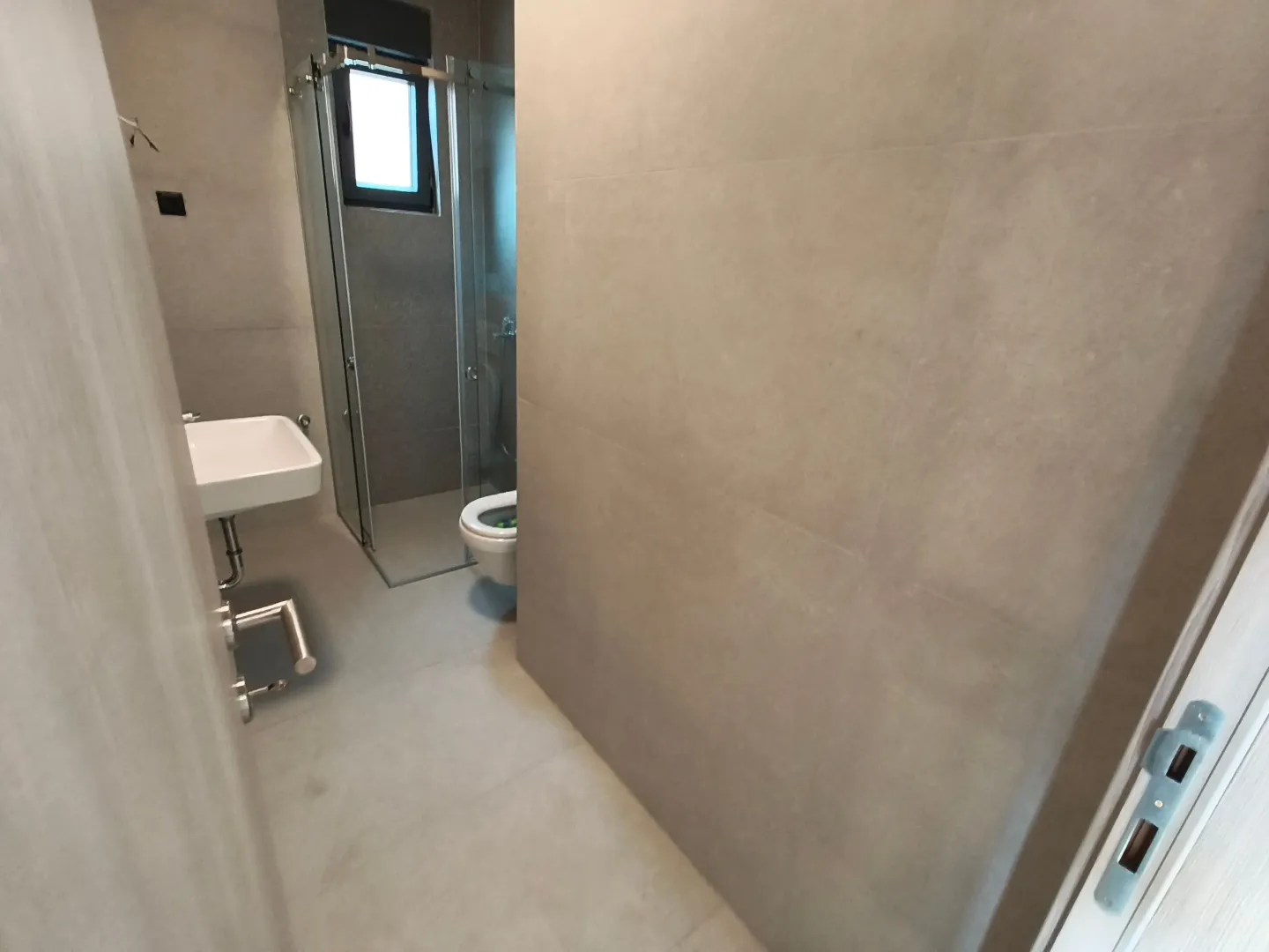Moderne kupatilo sa tuš kabinom, umivaonikom i toaletom.