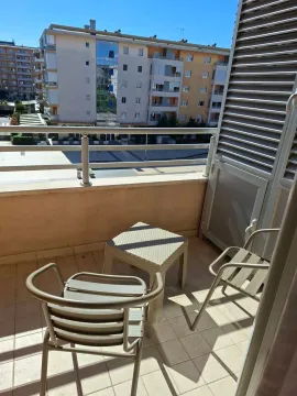 Furnished balcony with a table and chairs and a view of surrounding buildings. - image 7