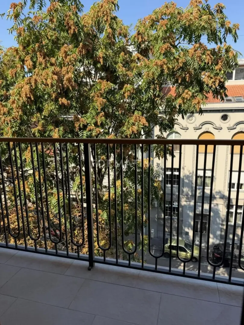 View from the balcony overlooking a tree and a neighboring building.