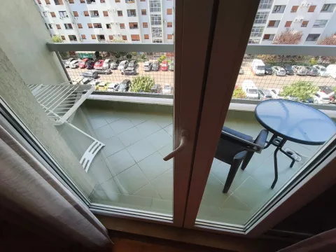 Manji balkon sa stolom, stolicom i sušilicom za veš, sa pogledom na parking zgrade. - image 9