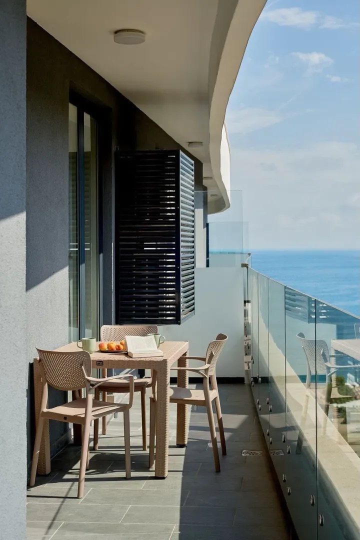 Moderan prostrani balkon sa garniturom za sjedenje i pogledom na more.