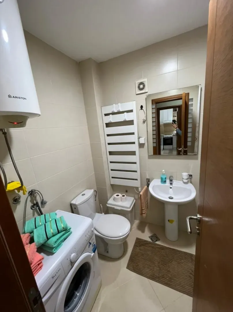Svijetlo kupatilo sa veš mašinom, lavaboom i ogledalom.