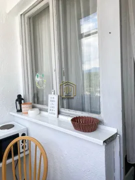 View of a glazed balcony with a small shelf, decorations, and part of a kitchen appliance. - image 10