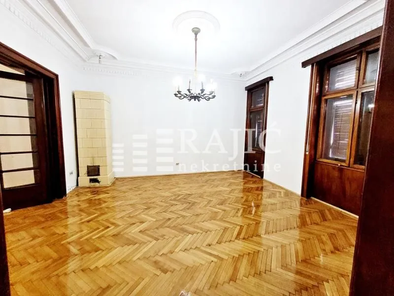 Empty living room with parquet flooring and decorative ceiling.