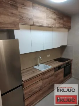 Opremljena kuhinja sa drvenim elementima i belim gornjim ormarićima. - image 5