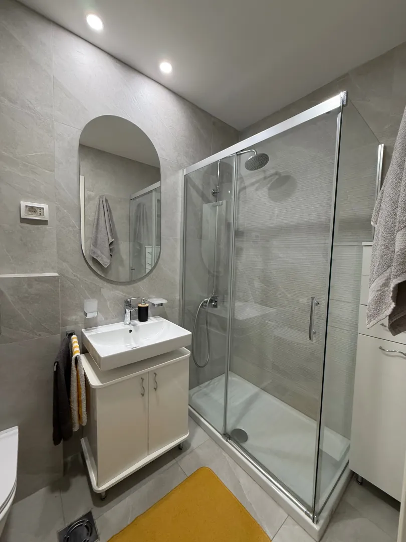 Modern bathroom with a sink, mirror, and glass walk-in shower.