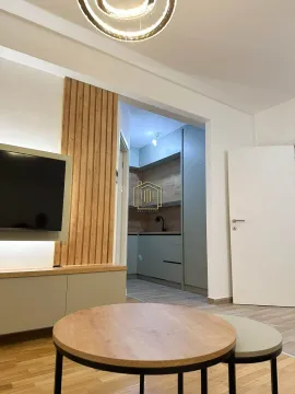 Pogled iz dnevne sobe prema kuhinji sa drvenim zidnim panelom i TV-om. - image 8