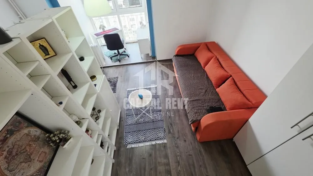 Living room with an orange sofa, a white shelving unit, and access to a glazed terrace.