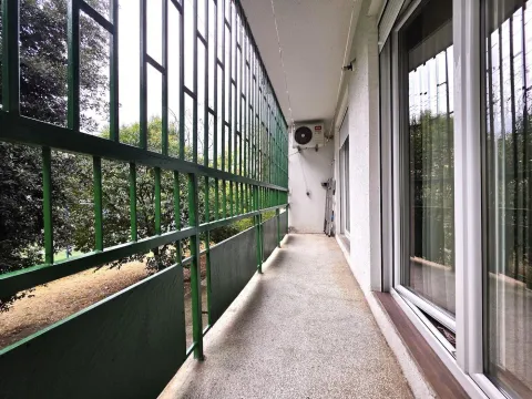 Long balcony with a metal railing and a view of greenery. - image 11