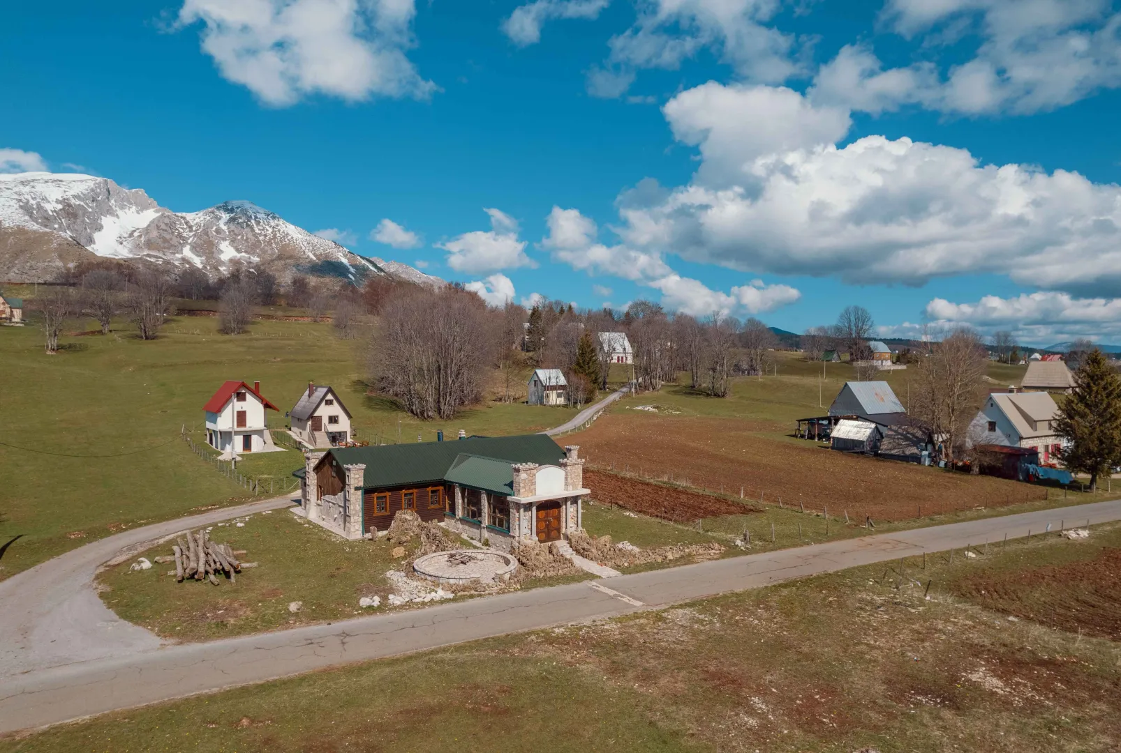 Aerial view of a rural property with houses and a mountain landscape in the background.