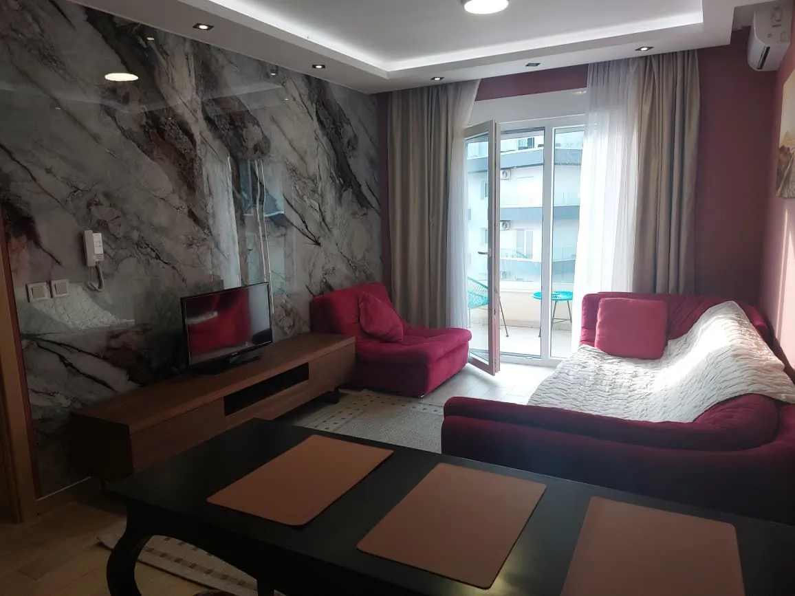 Living room with a red sofa set, TV, and balcony access.