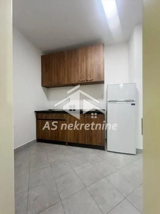 Small kitchen with wooden cabinets and a refrigerator.