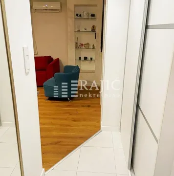 View from the hallway into a bright living room with seating furniture and built-in shelves. - image 6