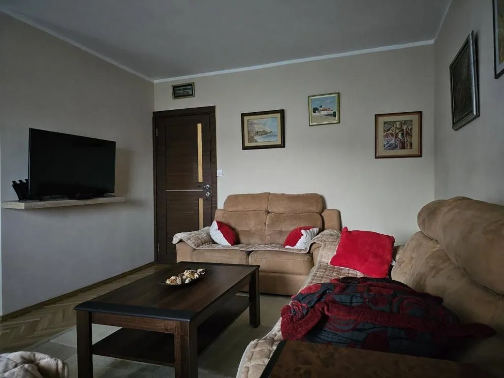 Dnevna soba sa garniturom, stočićem i televizorom.