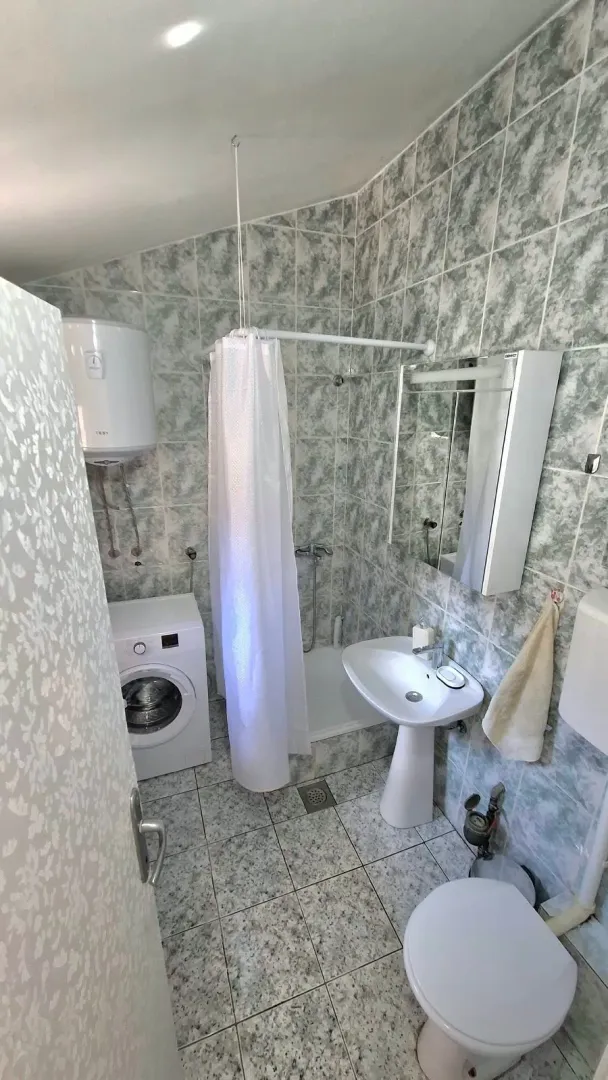 Bathroom with a shower cabin, washbasin, toilet, and washing machine.
