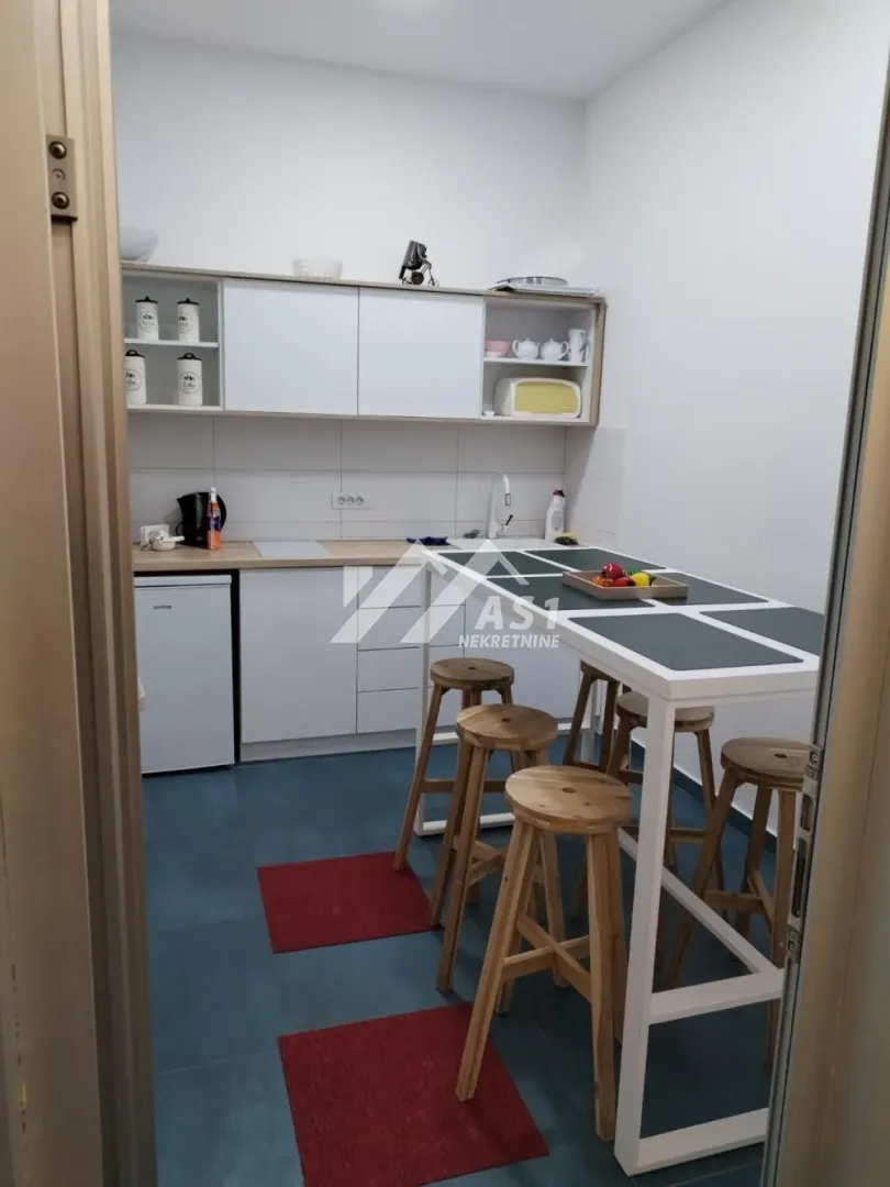 Small white kitchen with a bar and wooden bar stools.