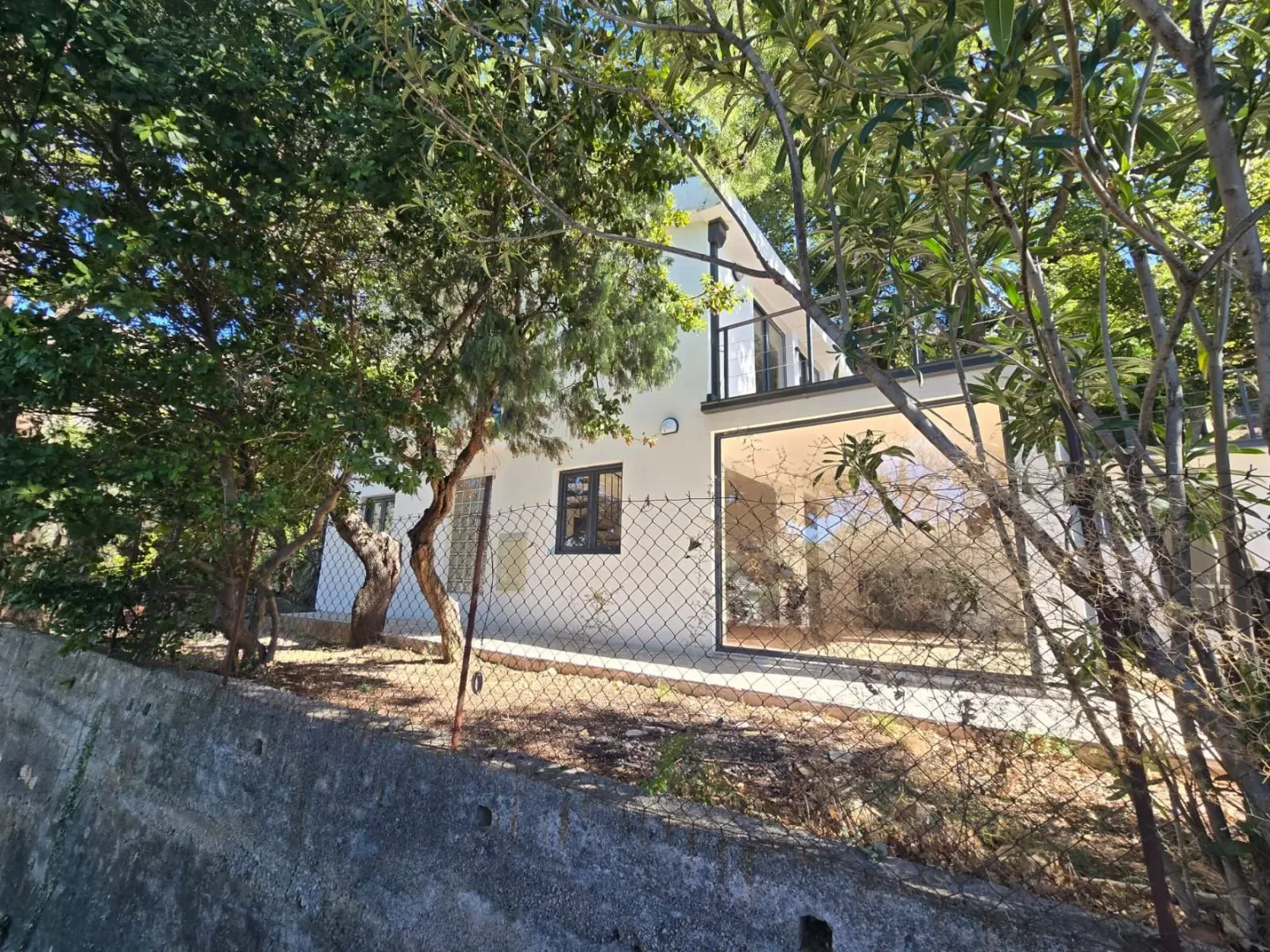 Pogled na spoljašnjost kuće sa dvorištem i ogradom.