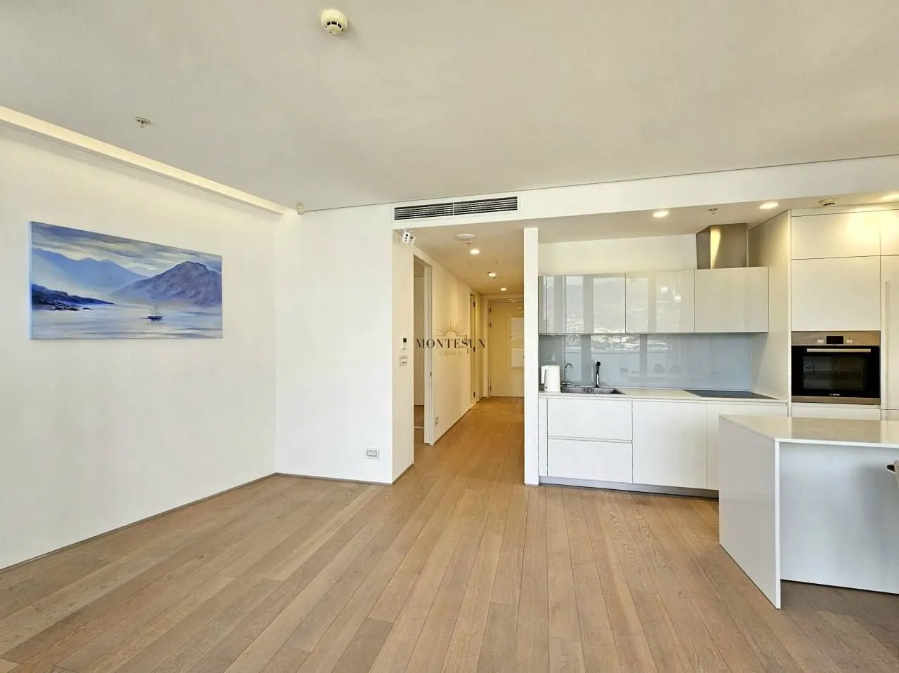 Modern bright living room connected to a white kitchen.