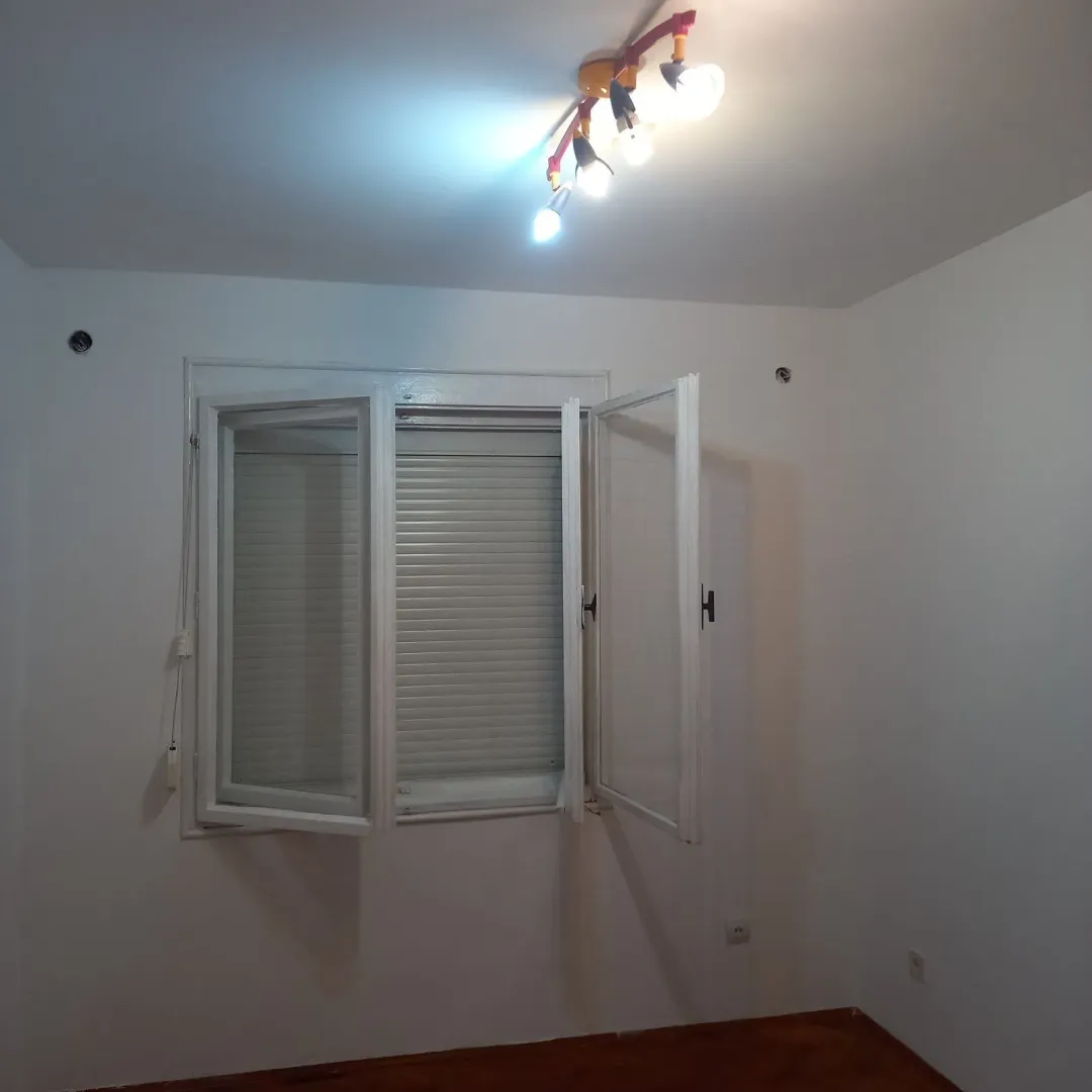 Empty room with white walls, a window with blinds, and a ceiling light fixture.