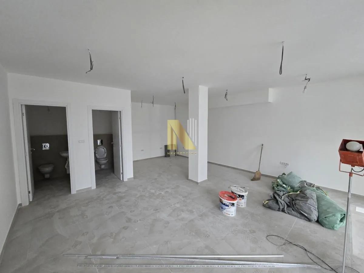 Unfinished commercial space with two toilets and construction material.