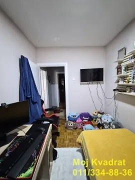 Manja spavaća soba sa krevetom, radnim stolom i televizorom. - image 10