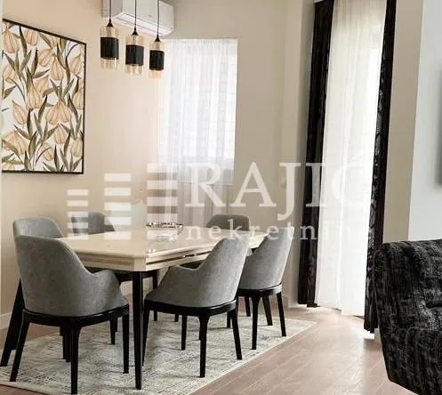 Modern dining area with a table and grey-black chairs.