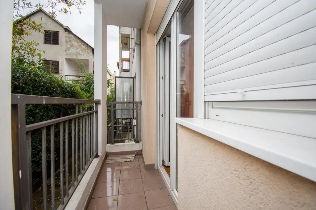 Narrow balcony with a metal railing and white shutters.