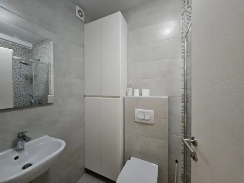 Modernly equipped bathroom with a sink, toilet, and white cabinet. - image 4
