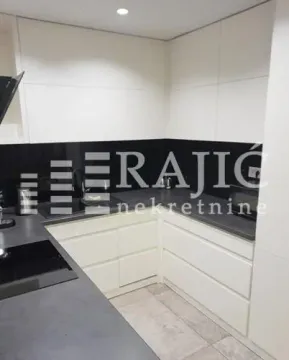 Modern kitchen with white cabinets and dark countertops. - image 4