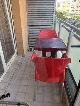 Balkon sa malim stolom i dvije crvene stolice. - image 2