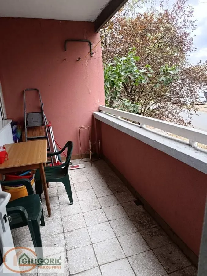 Namešten, odnosno opremljen balkon sa stolom, stolicama i pogledom na zelenilo.