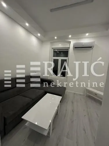 Living room with a sectional sofa, coffee table, and air conditioning unit.