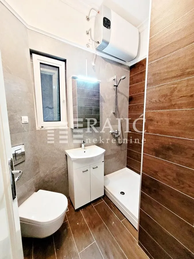 Small bathroom with a shower cabin, washbasin, and toilet.