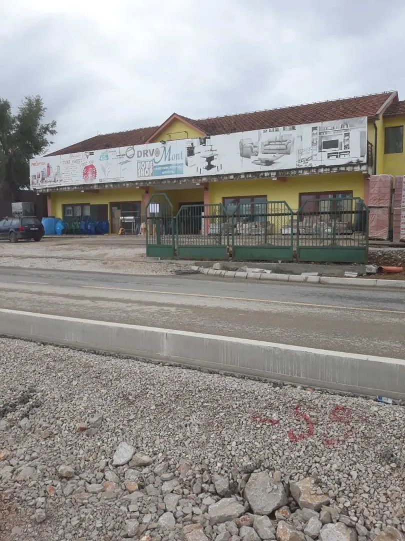 Exterior of a commercial building with a yellow facade and an advertising banner.
