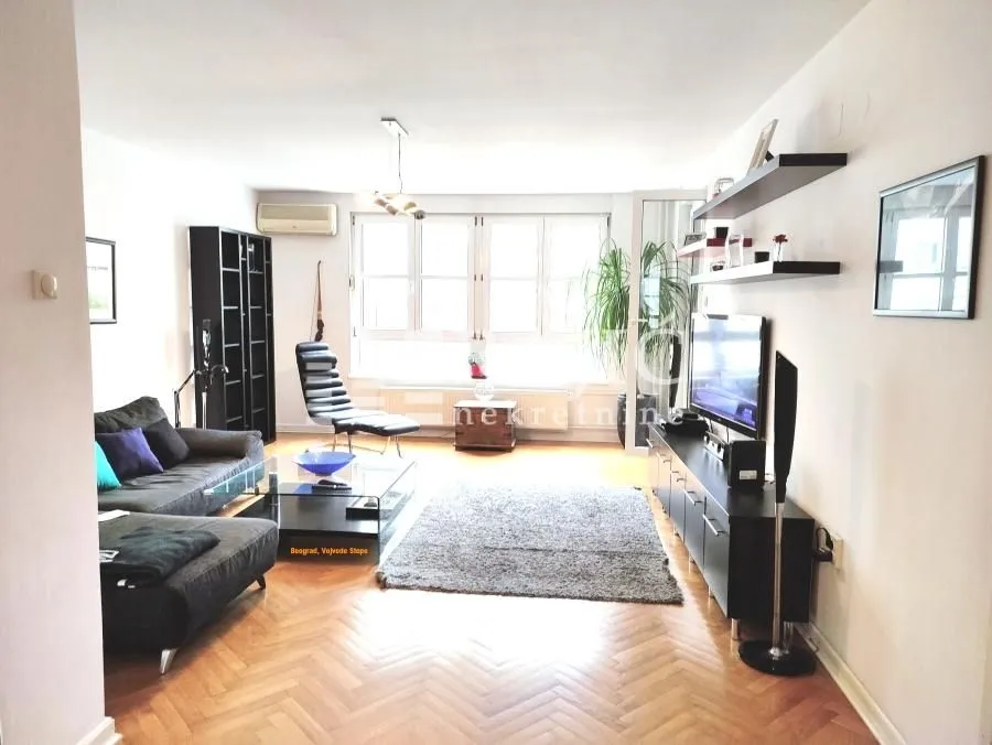 Spacious living room with sofa, TV and parquet flooring.