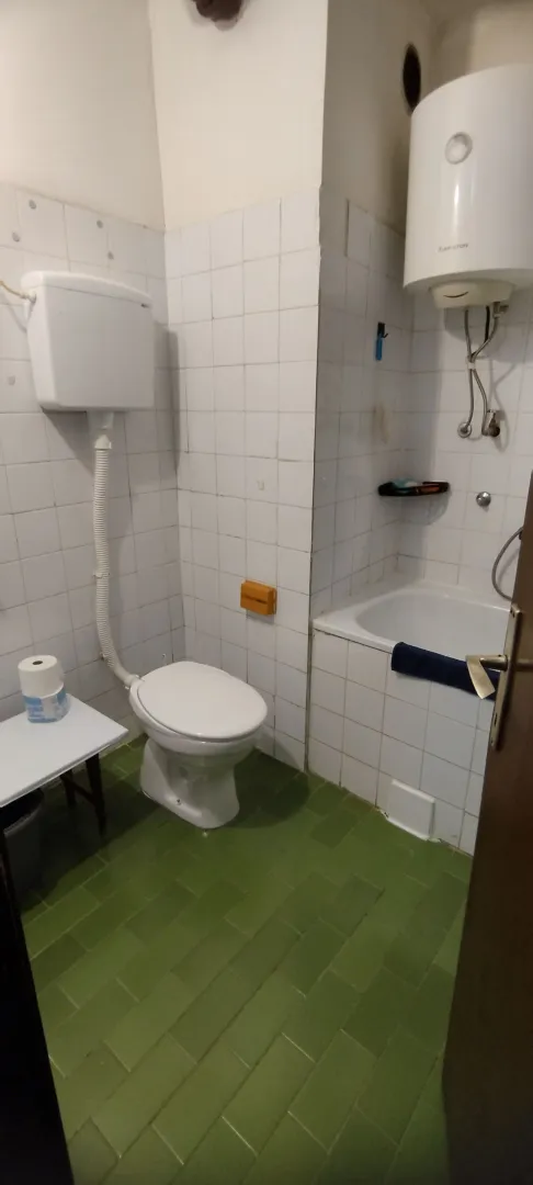 Manje kupatilo sa bijelim pločicama, kadom i wc šoljom.