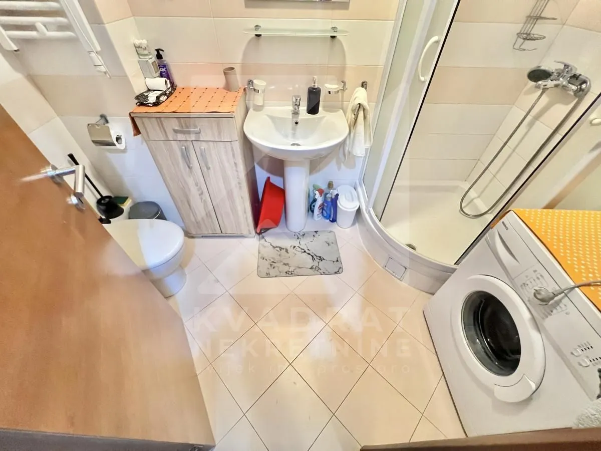 Bathroom with a shower cabin, washbasin, toilet, and washing machine.