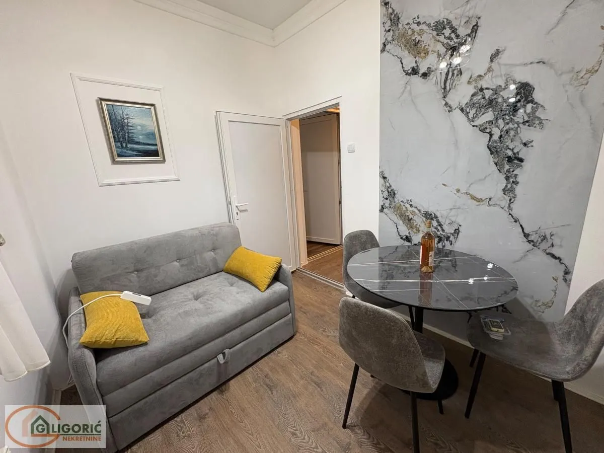 Small living room with a grey sofa, dining table, and chairs.