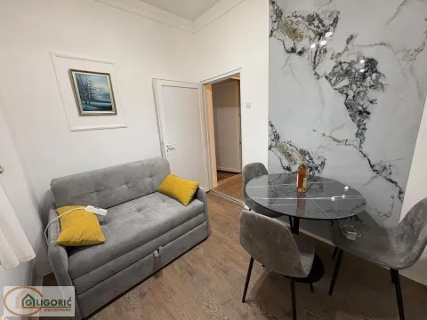 Small living room with a grey sofa, dining table, and chairs. - image 5