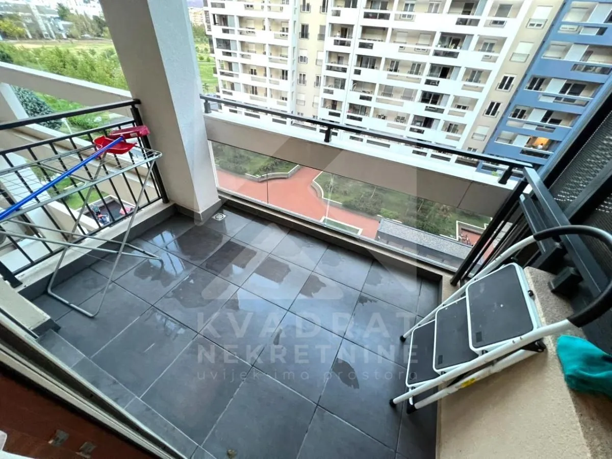 A small tiled balcony with a railing and a view of surrounding buildings.