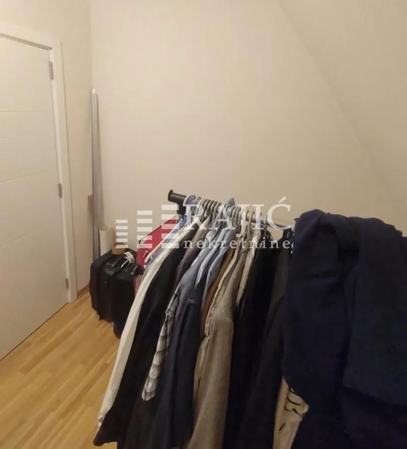 View of part of the room with a clothes rack and a door.