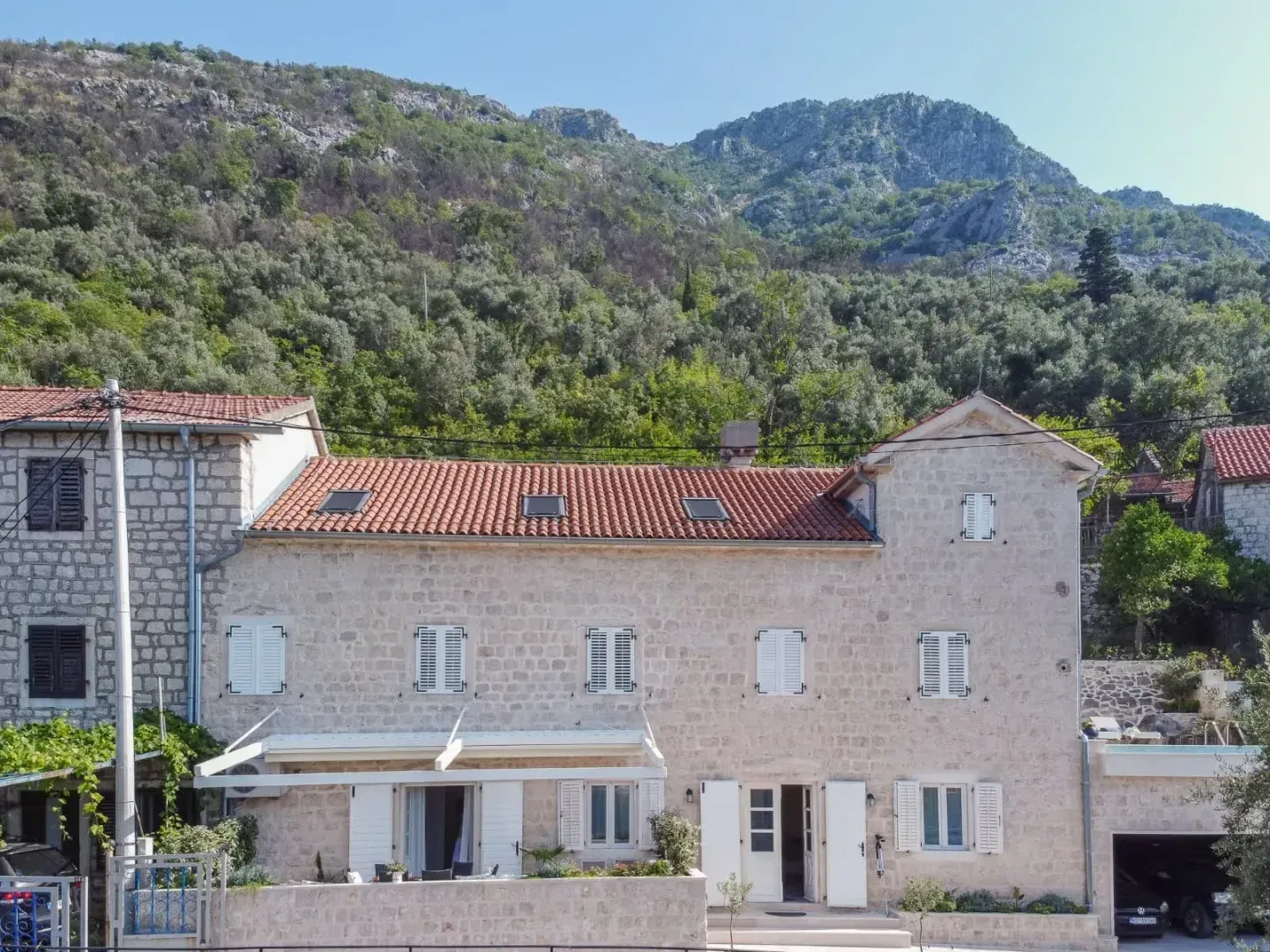 View of the facade of a traditional stone house with a mountain background.
