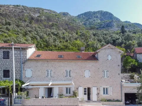 View of the facade of a traditional stone house with a mountain background. - image 9