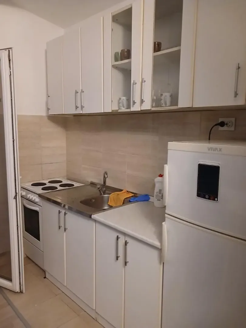 Manja bijela kuhinja sa štednjakom i frižiderom.