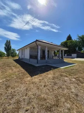 Pogled na spoljašnjost prizemne kuće sa uređenim dvorištem i terasom. - image 2