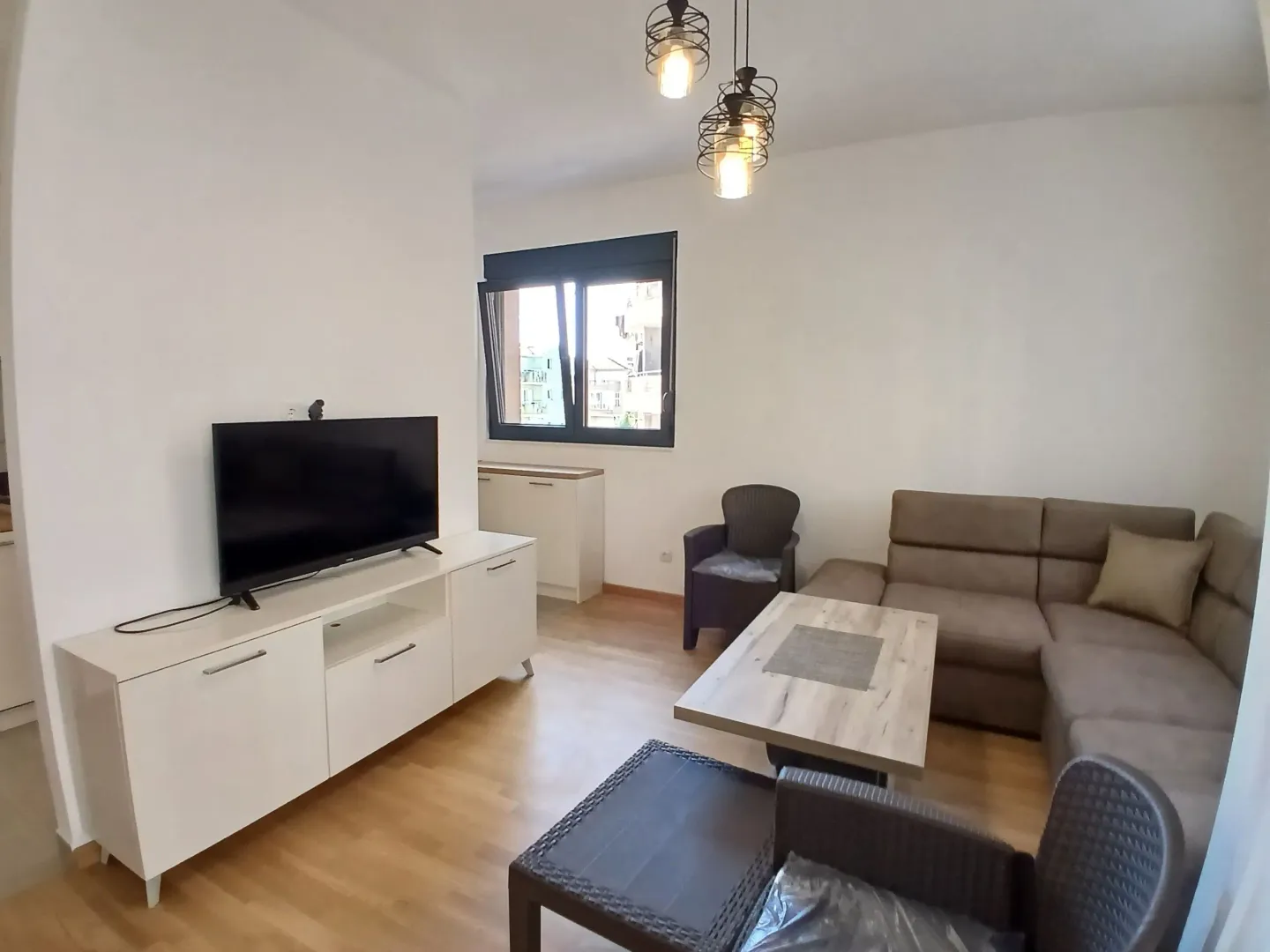 Dnevna soba sa garniturom, televizorom i trpezarijskim stolom.
