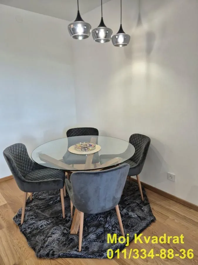 A dining table with four glass and upholstered chairs in the corner of the room.